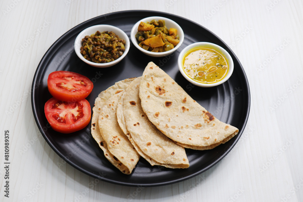 Roti and bhaji. Indian vegetarian Thali or platter includes akhha Masoor sabzi, dal, fansi or beans ki sabji, and chapati. Indian food is served in a plate or thali. Copy Space. healthy Veg Thali. Roti and bhaji. Indian vegetarian Thali or platter includes akhha Masoor sabzi, dal, fansi or beans ki sabji, and chapati. Indian food is served in a plate or thali. Copy Space. healthy Veg Thali.
