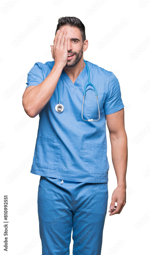 Handsome young doctor surgeon man over isolated background covering one eye with hand with confident smile on face and surprise emotion. Handsome young doctor surgeon man over isolated background covering one eye with hand with confident smile on face and surprise emotion.