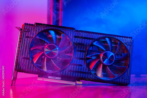 Powerful modern GPU Video Card with two fans with PC case on background in neon light. Rendering and gaming computer hardware components. photo