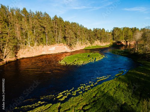 breathtaking aerial view of a river meandering through lush green landscapes with red cliff banks