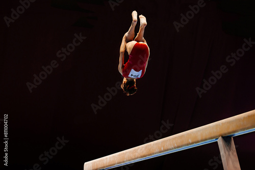 female gymnast perform backward somersault exercise on balance beam gymnastics