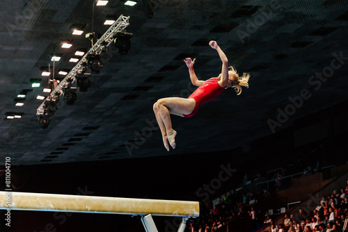 exercise on balance beam gymnastics, female gymnast perform backward somersault landing on floor