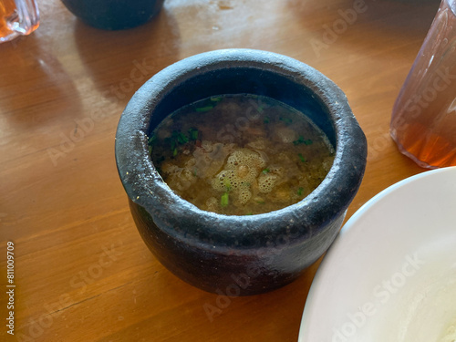 Empal gentong, traditional meat soup from Cirebon, Indonesia. In small clay pot, on wooden table photo