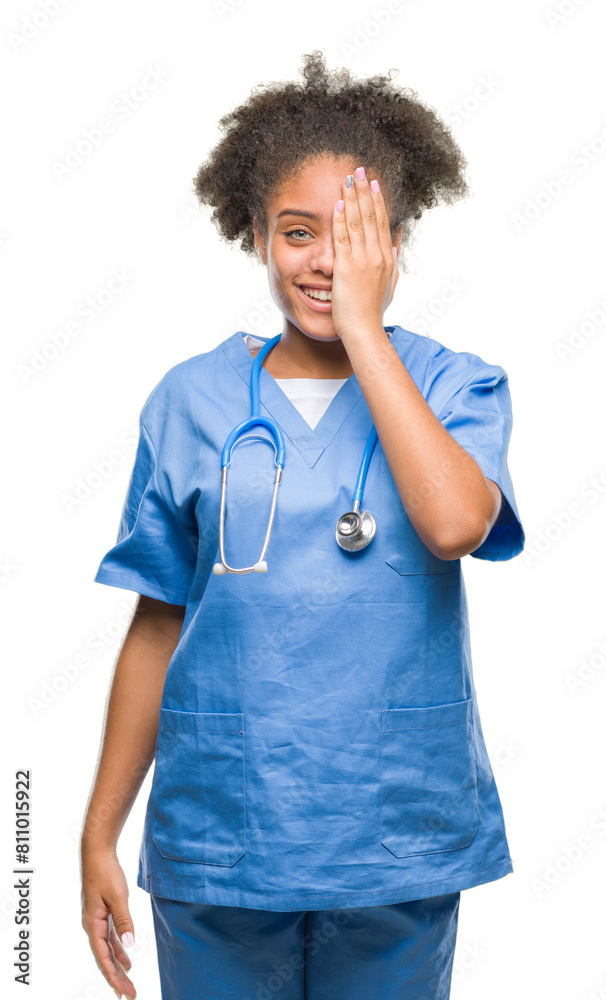 Young afro american doctor woman over isolated background covering one eye with hand with confident smile on face and surprise emotion. Young afro american doctor woman over isolated background covering one eye with hand with confident smile on face and surprise emotion.