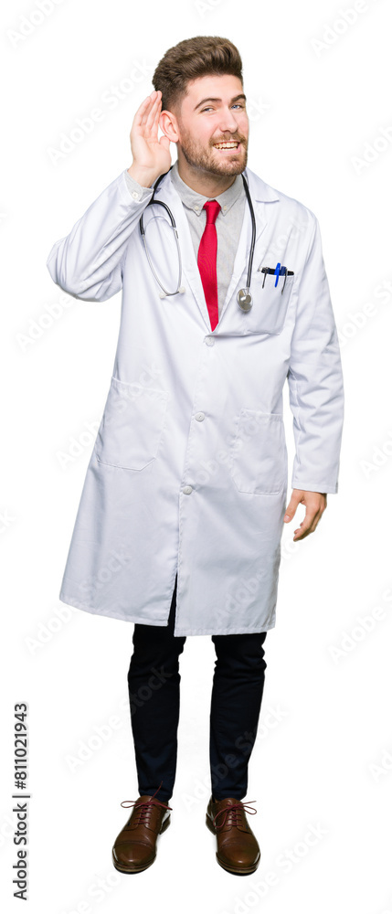 Young handsome doctor man wearing medical coat smiling with hand over ear listening an hearing to rumor or gossip. Deafness concept. Young handsome doctor man wearing medical coat smiling with hand over ear listening an hearing to rumor or gossip. Deafness concept.