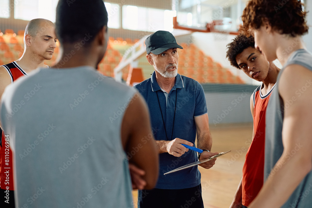 Basketball coach and his team going through game strategy before match. Basketball coach and his team going through game strategy before match.