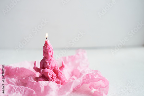 A pink candle is placed on a pink petal, resembling a delicate flower. The magenta hue contrasts beautifully with the natural material, creating a stunning visual in macro photography