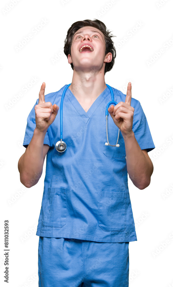 Young doctor wearing medical uniform over isolated background amazed and surprised looking up and pointing with fingers and raised arms. Young doctor wearing medical uniform over isolated background amazed and surprised looking up and pointing with fingers and raised arms.