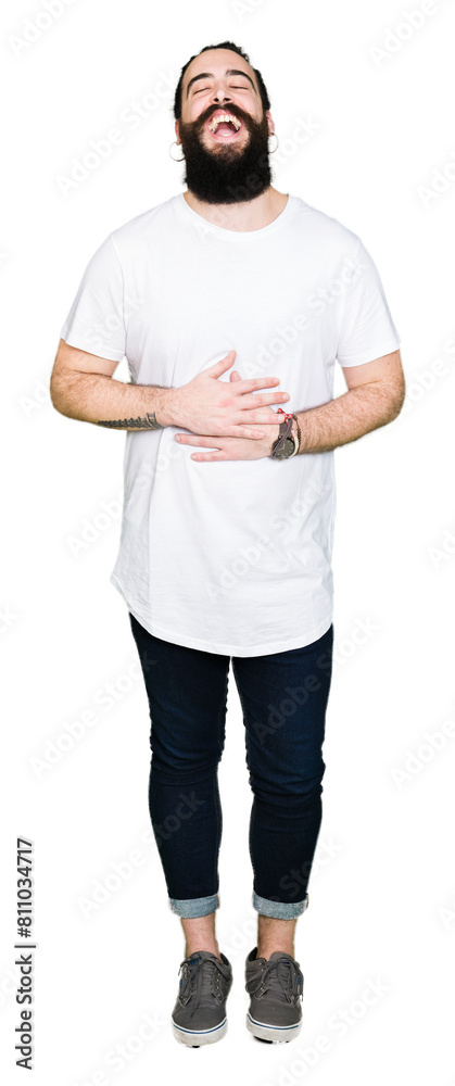 Young hipster man with long hair and beard wearing casual white t-shirt Smiling and laughing hard out loud because funny crazy joke. Happy expression. Young hipster man with long hair and beard wearing casual white t-shirt Smiling and laughing hard out loud because funny crazy joke. Happy expression.