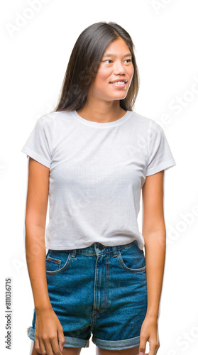 Young asian woman over isolated background looking away to side with smile on face, natural expression. Laughing confident.