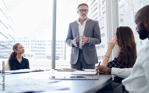Businessman, mentor and meeting with team for presentation, corporate discussion or coaching at office. Man, CEO or executive talking to group of employees for business strategy or ideas at workplace