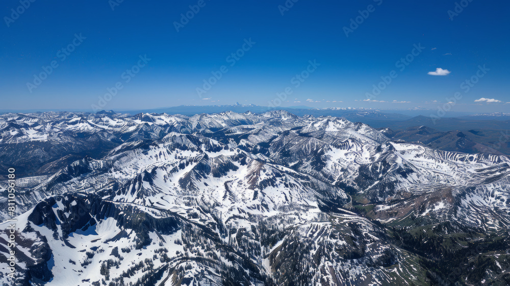 Fototapeta premium high-altitude drone photograph of snow-capped mountains under clear blue skies