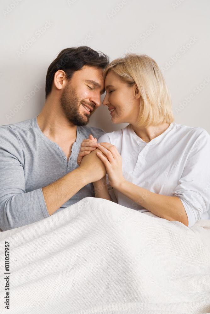 Image of closed eyes, holding hands man and woman, leaning their heads on each other, married inlove couple at bedroom, praying in home bed. Waiting child, planning pregnancy, plea concept. Image of closed eyes, holding hands man and woman, leaning their heads on each other, married inlove couple at bedroom, praying in home bed. Waiting child, planning pregnancy, plea concept.