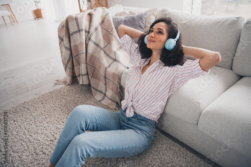 Photo of adorable sweet lady wear white shirt earphones listening songs arms behind head indoors room home house