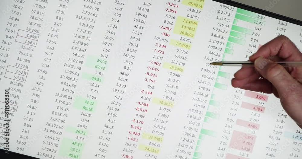 Spreadsheet with changing data and hand holding pen pointing to numbers