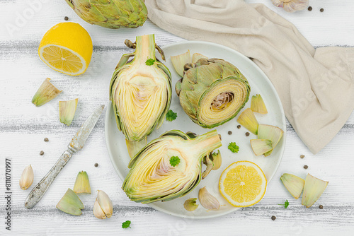 Fresh green artichokes cooking on wooden background. Traditional seasonal ingredients photo