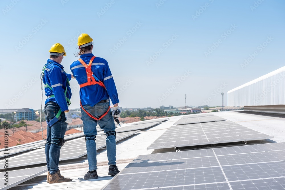 Two solar panel workers installing solar panels on a roof. Two solar panel workers installing solar panels on a roof.
