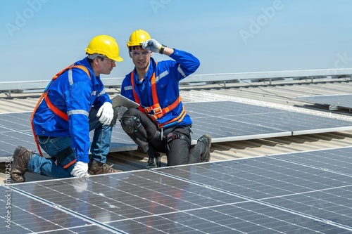 Wallpaper Mural Two solar panel engineers wearing safety gear are inspecting a rooftop solar panel installation. Torontodigital.ca