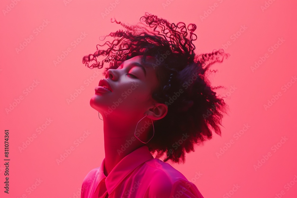 Stylish African American woman in pink with eyes closed against a vibrant red background, exuding elegance and confidence.
Stylish African American woman in pink with eyes closed against a vibrant red background, exuding elegance and confidence.