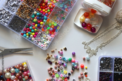Colorful beads, letter beads, threads and other jewelry making supplies on white background. Making friendship bracelets concept. Flat lay.