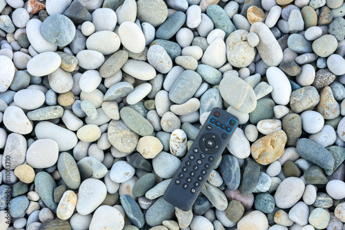 TV remote control on smooth sea pebbles