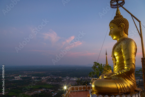 Scenic view of the surrounding area and a big golden Buddha statue on top of the mountain at the Tiger Cave Temple (Wat Tham Suea (Sua)) in Krabi, Thailand, at dusk. photo