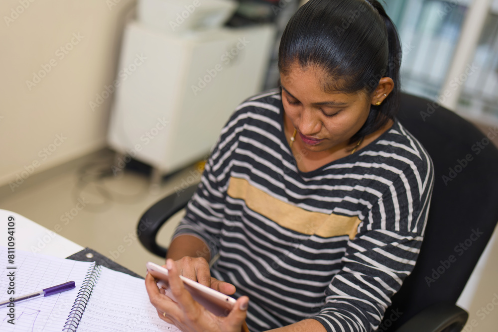 Young woman using tablet at desk in office. Side view. Young woman using tablet at desk in office. Side view.