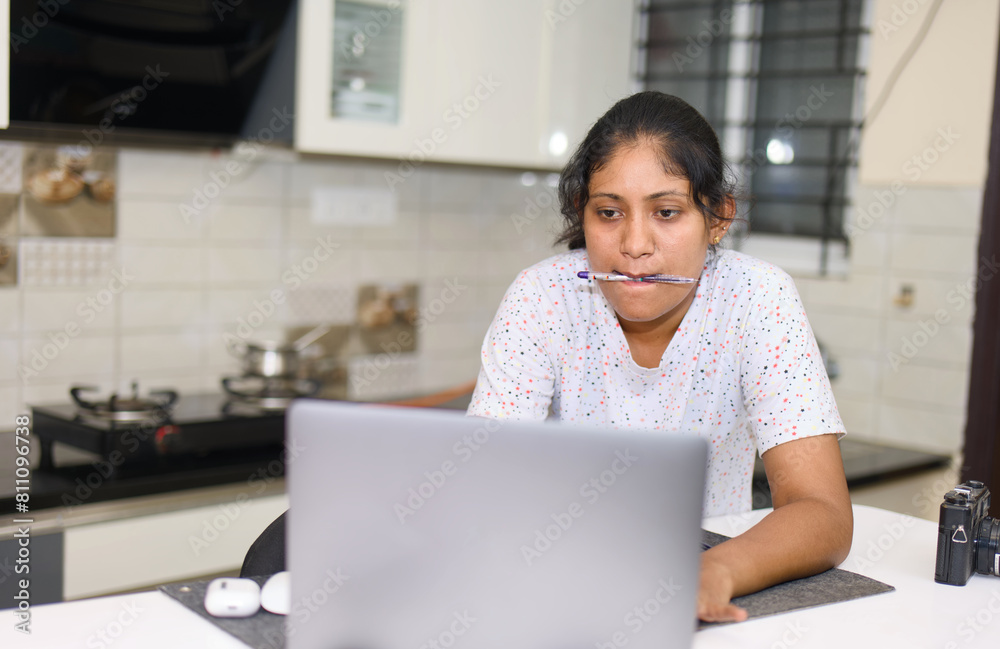 Young indian woman using a laptop computer in the kitchen at home Young indian woman using a laptop computer in the kitchen at home