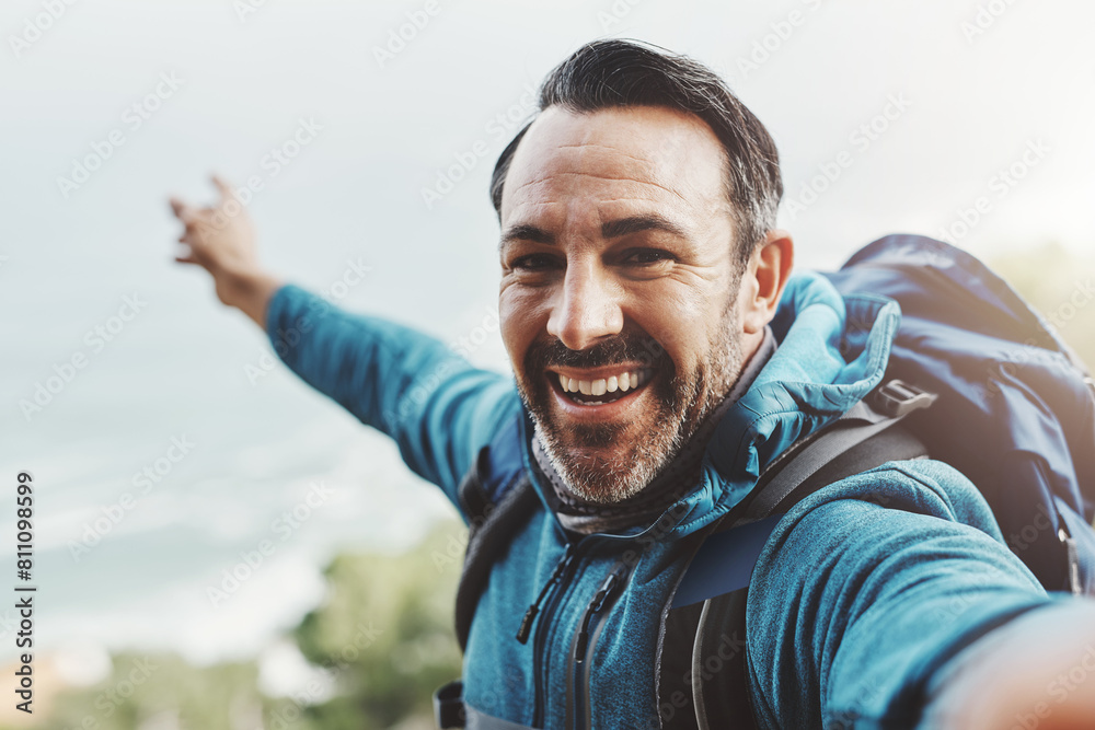 Naklejka premium Selfie, hiking and man with nature, travel and excited with happiness, adventure or environment. Portrait, person or hiker with profile picture, health or vacation with journey, getaway trip or smile