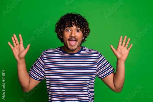 Photo of cheerful glad funky man wear stylish striped clothes rejoice news isolated on green color background