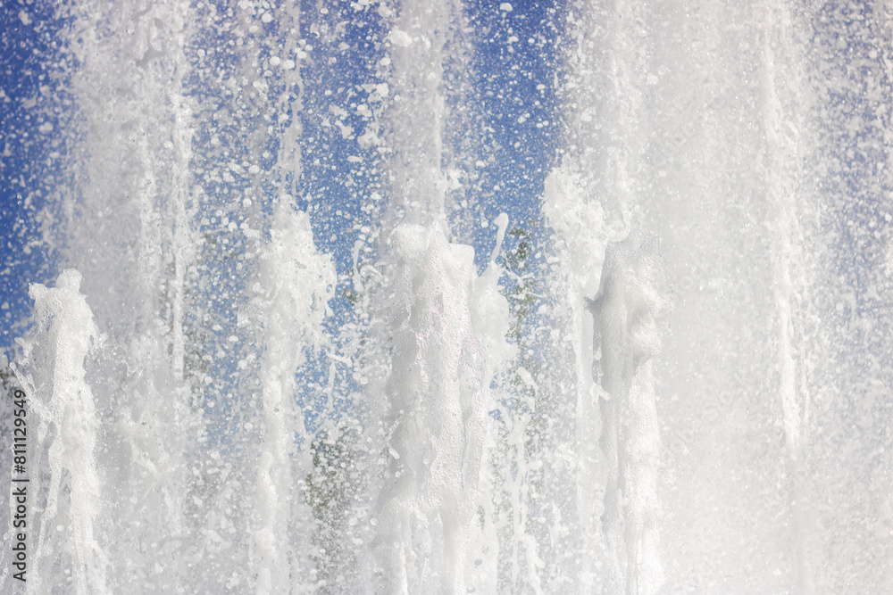 Water fountain splashing liquid against an electric blue sky Water fountain splashing liquid against an electric blue sky