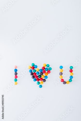 many colored ludo pawns strung together forming the word "I heart U" on white background