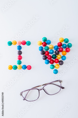 ludo tokens forming the word "I heart" and a pair of eyeglasses on white background