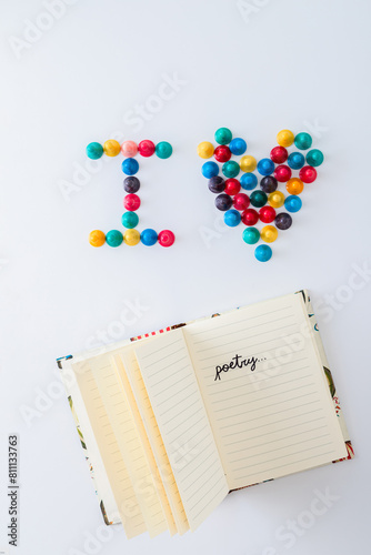 ludo tokens forming the word "I heart" and an open lined notebook with the word "poetry" written on it