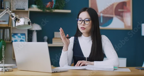 Cute Asian businesswoman or freelancer wearing glasses to use laptop. Hardworking woman participating in meeting with her investors or work colleagues. Discussing something for business improvement.