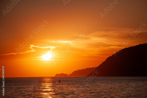Sunset on ipanema beach  with Morro Dois Irm  os in the background and people practicing standup paddle in the sea water  during the version in the city of Rio de Janeiro.