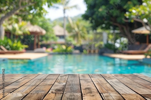 Empty wood table top and blurred swimming pool in tropical resort in summer banner background