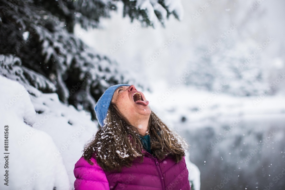 A middle aged woman trying to catch a snowflake on her tongue on a cold snowy day in Colorado, Vail A middle aged woman trying to catch a snowflake on her tongue on a cold snowy day in Colorado, Vail