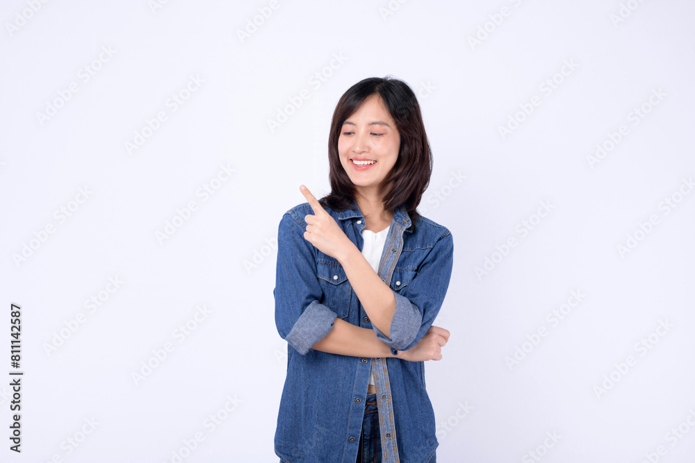A young asian woman wearing denim jean while pointing finger to free copy space isolated on white studio background A young asian woman wearing denim jean while pointing finger to free copy space isolated on white studio background