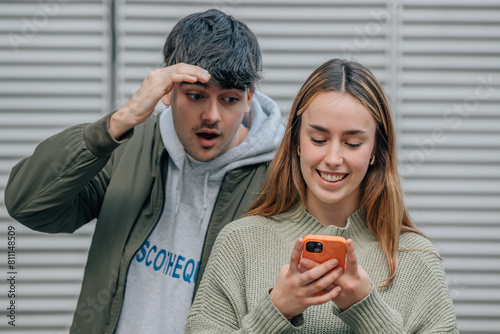 Fotografie couple spying and looking at mobile phone