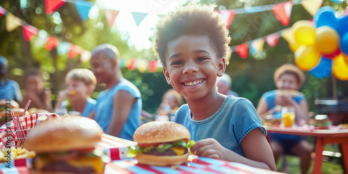 The image of a small African-American boy sitting at the dining table and eating hamburgers with an appetite reflects the idea of celebrating U.S. Independence Day, which is celebrated on July 4.