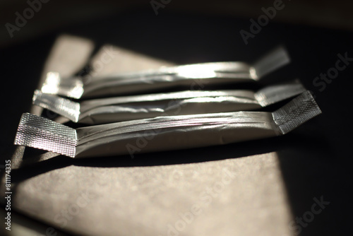 Three white medicine sticks on a gray background in bright sunlight. Close-up with blurred background.