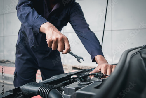Mechanic using wrench while working on car engine outside the service center , Repair and service. © Nonthanat