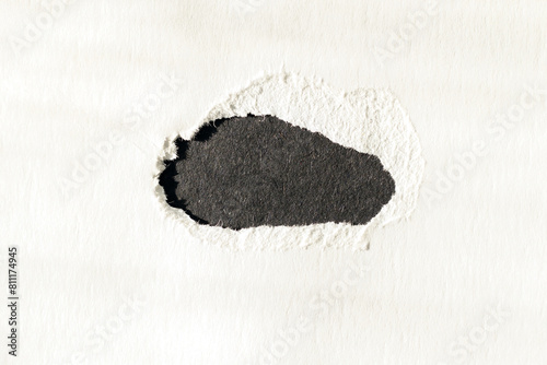 White cardboard with a large black hole. Close-up view from above.