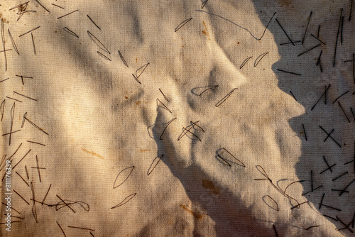 An old gray tarpaulin stitched with black threads. Close-up view from above.
