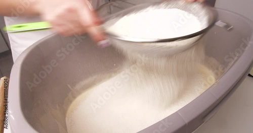 A confectioner sifts flour to knead the dough for baking a confectionery product. photo