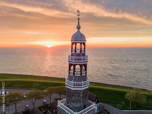 Aerial drone image of historic small city of Hindeloopen, Hylpen with dike, marina, seawall, next to IJsselmeer lake with iconic church and village during spectacular sunset photo