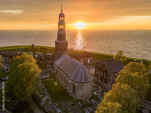 Aerial drone image of historic small city of Hindeloopen, Hylpen with dike, marina, seawall, next to IJsselmeer lake with iconic church and village during spectacular sunset
