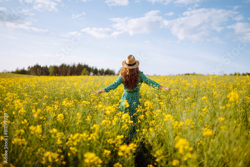 Beautiful woman walks run along yellow field rapeseed. Nature, fashion, summer lifestyle.