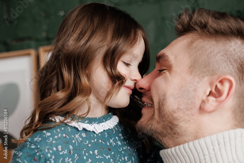 Happy Father's Day. Smiling young dad embraces with big hug his adorable little child daughter at home. Single daddy and small kid hug cuddle enjoy sweet moments together. Fatherhood. Children's day